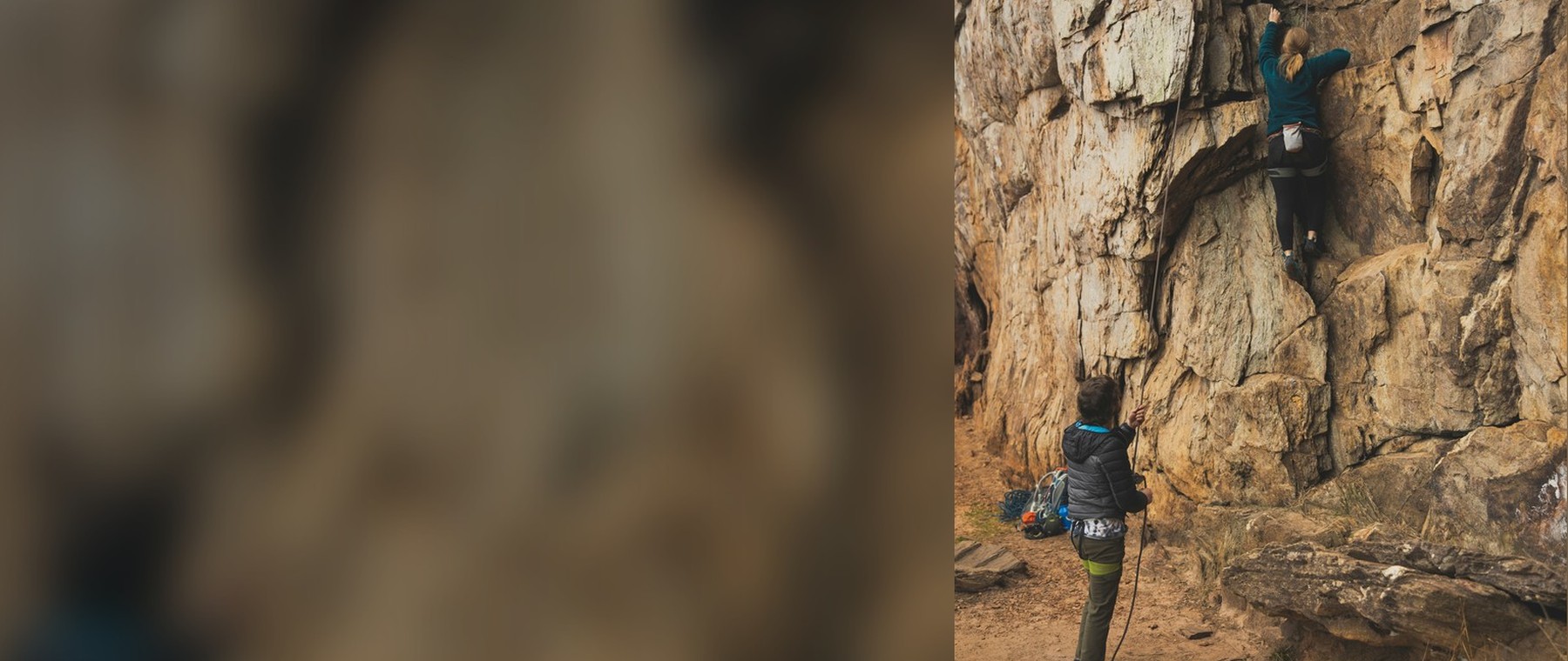 Two female climbers, one climbing and one belaying