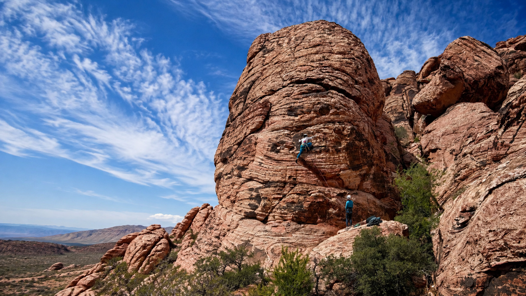 A climber on Red Rock sandstone with a belayer below